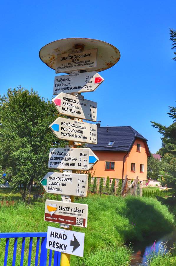 Biała tabliczka z napisem „Brníčko”, słup z drogowskazami