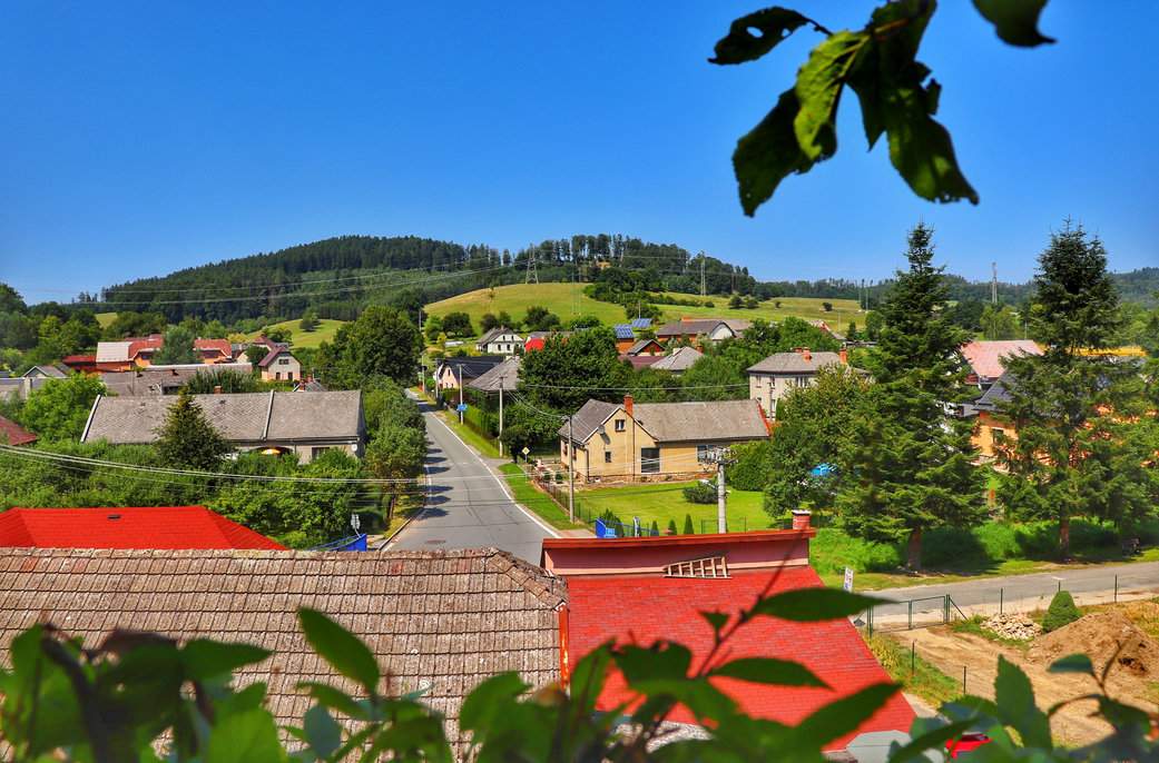 Widok na malownicze zabudowania i drogę w Brníčku, uchwycony ze szlaku prowadzącego do ruin zamku