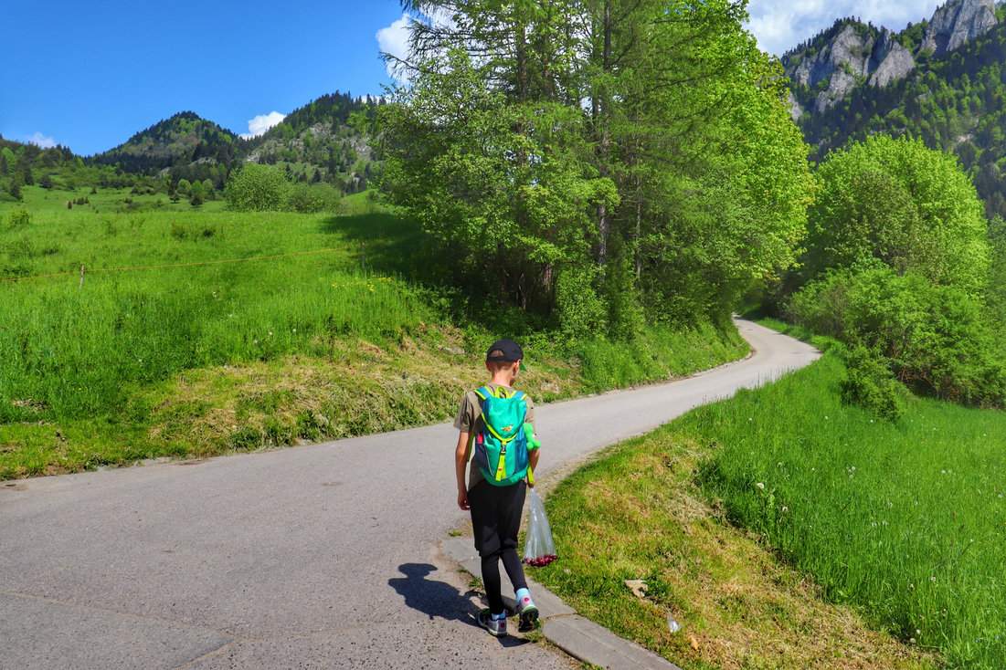 Dziecko idące na Trzy Korony w Pieninach, szeroka asfaltowa droga, słoneczne przedpołudnie