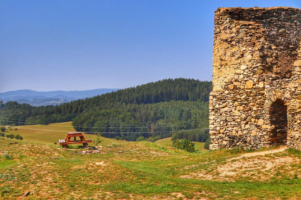 Widok rozciągający się z okolic ruin zamku Brníčko w Czechach – górski krajobraz w pełni lata, pełen zieleni i słońca