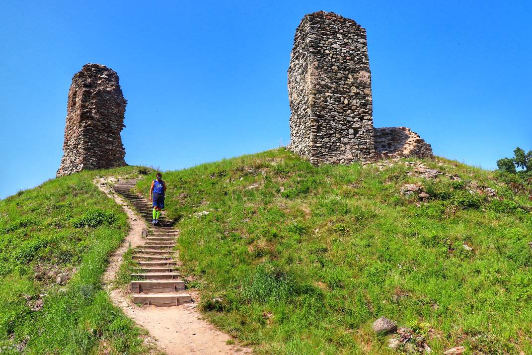 Turysta schodzący po schodach, w tle ruiny zamku Brníčko, Czechy