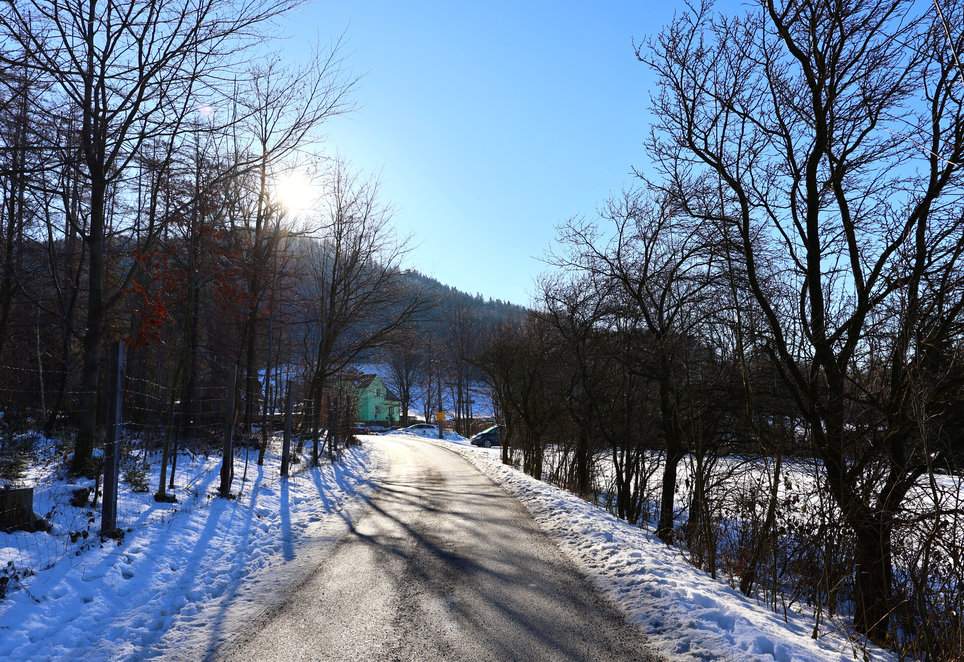Szeroka, asfaltowa droga na czerwonym szlaku prowadzącym do Chaty Prašivá - słoneczne, zimowe popołudnie