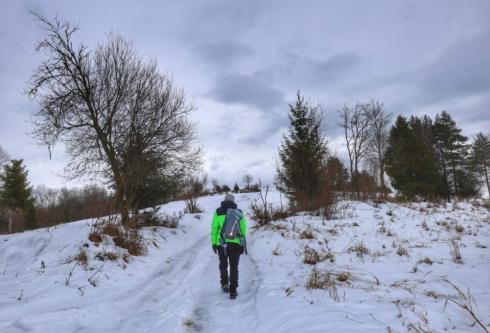 Turysta na szlaku na Gładki Wierch (Hladký vrch) na Słowacji, idący w górę zaśnieżonej polany