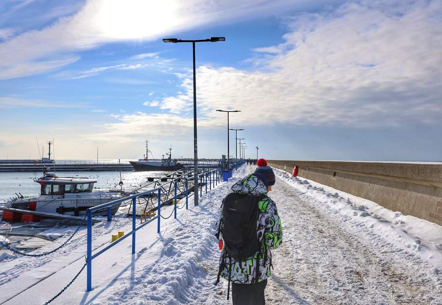 Spacer dziecka po zachodnim falochronie w Helu podczas słonecznego zimowego dnia