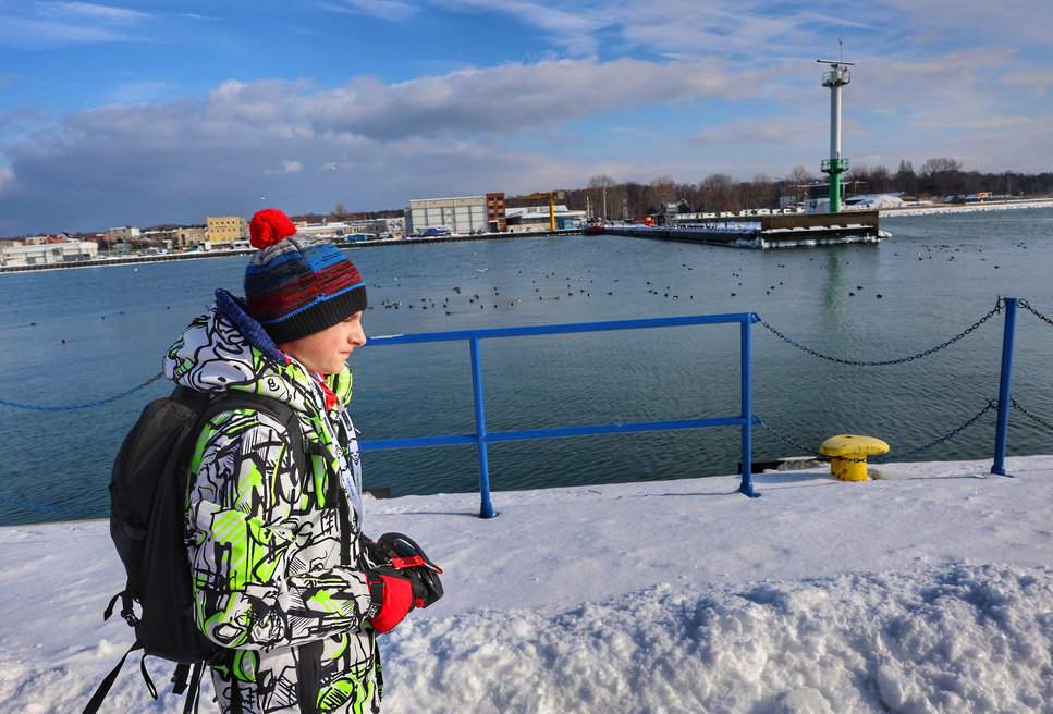 Dziecko na zachodnim falochronie przy Porcie Morskim w Helu podczas słonecznego zimowego dnia