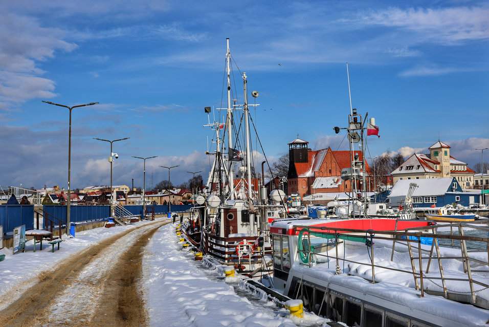 Widok z zachodniego falochronu na Port Morski w Helu, w oddali budynek Muzeum Rybołówstwa