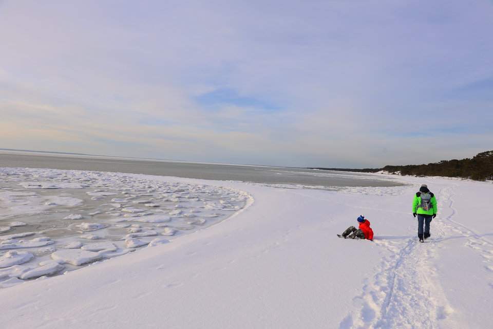 Piękna, szeroka plaża w Helu na Mierzei Helskiej - śnieg, błękitne niebo, turysta z dzieckiem