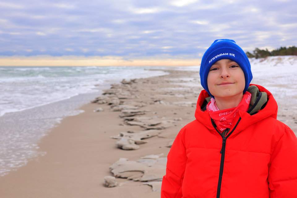 Uśmiechnięte dziecko na plaży, w tle morze - Hel