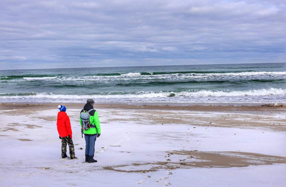Turysta z dzieckiem podziwiający zimowy Bałtyk w Helu