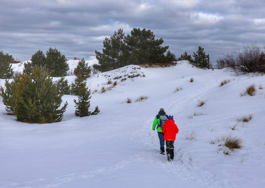 Turysta z dzieckiem na zaśnieżonej ścieżce edukacyjnej „Helskie Wydmy” w Helu