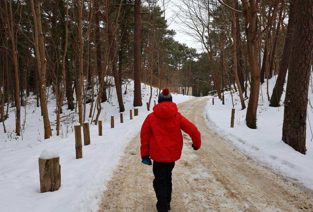 Dziecko idące szeroką, zaśnieżoną drogą w kierunku wieży widokowej w Juracie