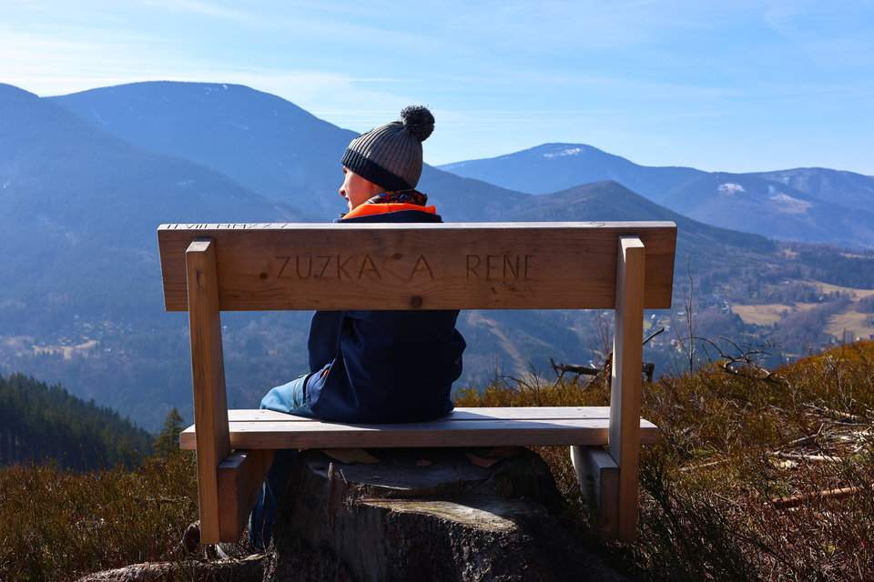 Dziecko siedzące na drewnianej ławce, w tle widok na beskidzkie szczyty - punkt widokowy Smrčina w Czechach