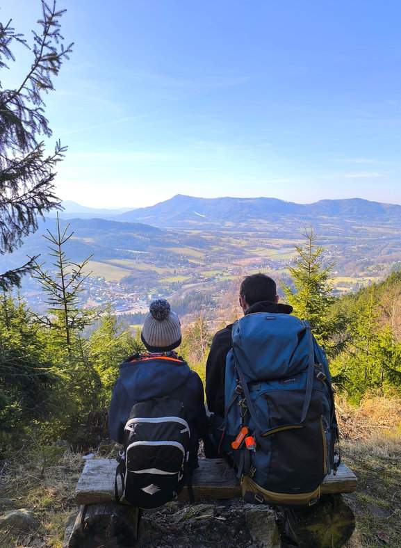 Turysta z dzieckiem na ławeczce podziwia widoki z punktu widokowego na Ostravicę i Ondřejník w Beskidzie Morawsko-Śląskim