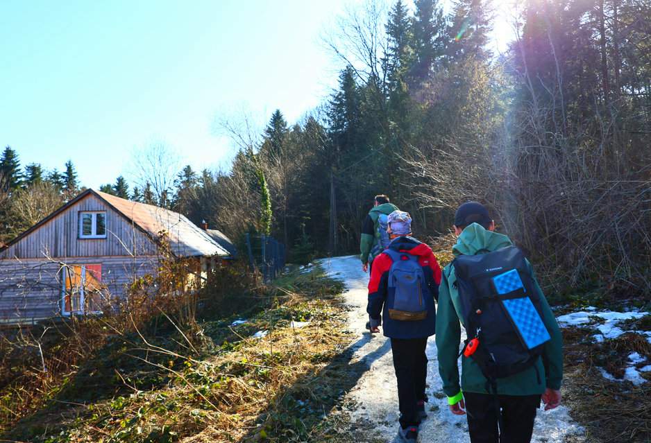 Turysta z dwójką dzieci na wąskiej, oblodzonej ścieżce przez wzniesienie Gruszyn w Beskidzie Wyspowym