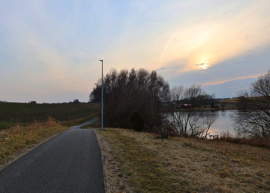 Szeroka, asfaltowa droga prowadząca wokół zbiornika „Źródlana Oaza” w Marklowicach - zachód słońca