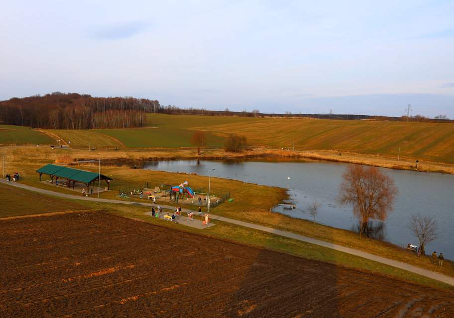 Widok na tereny rekreacyjne „Źródlana Oaza” - zadaszoną wiatę, plac zabaw, siłownię na świeżym powietrzu oraz staw