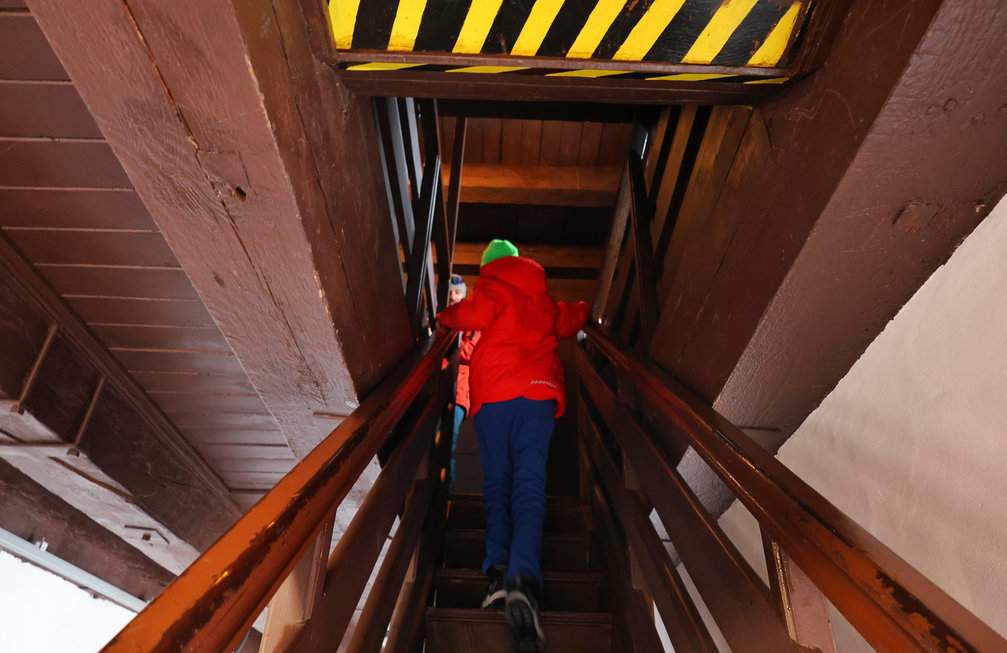 Dziecko wspinające się po stromych, drewnianych schodach na wieżę widokową w Muzeum Rybołówstwa w Helu