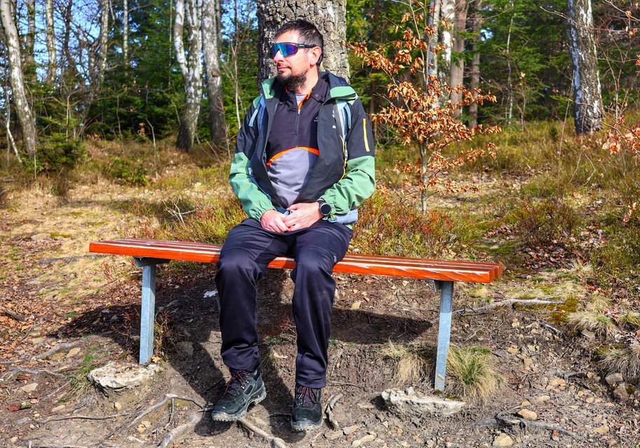 Turysta siedzący na ławce przy czerwonym szlaku idącym w kierunku Babicy w Beskidzie Makowskim, podziwiający widoki rozciągające się ze szlaku