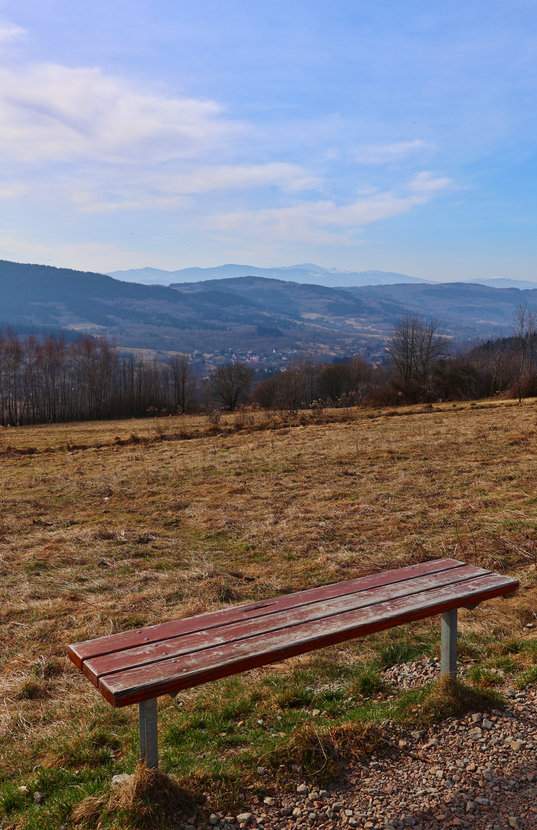 Polana z ławeczką i widokiem na Beskid Żywiecki z czerwonego szlaku prowadzącego na Babicę w Beskidzie Makowskim