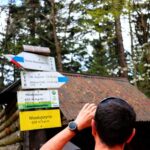 Turysta przy słupie z drogowskazami i żółtą tabliczką „Mioduszyna 632 m n.p.m.” - Beskid Makowski